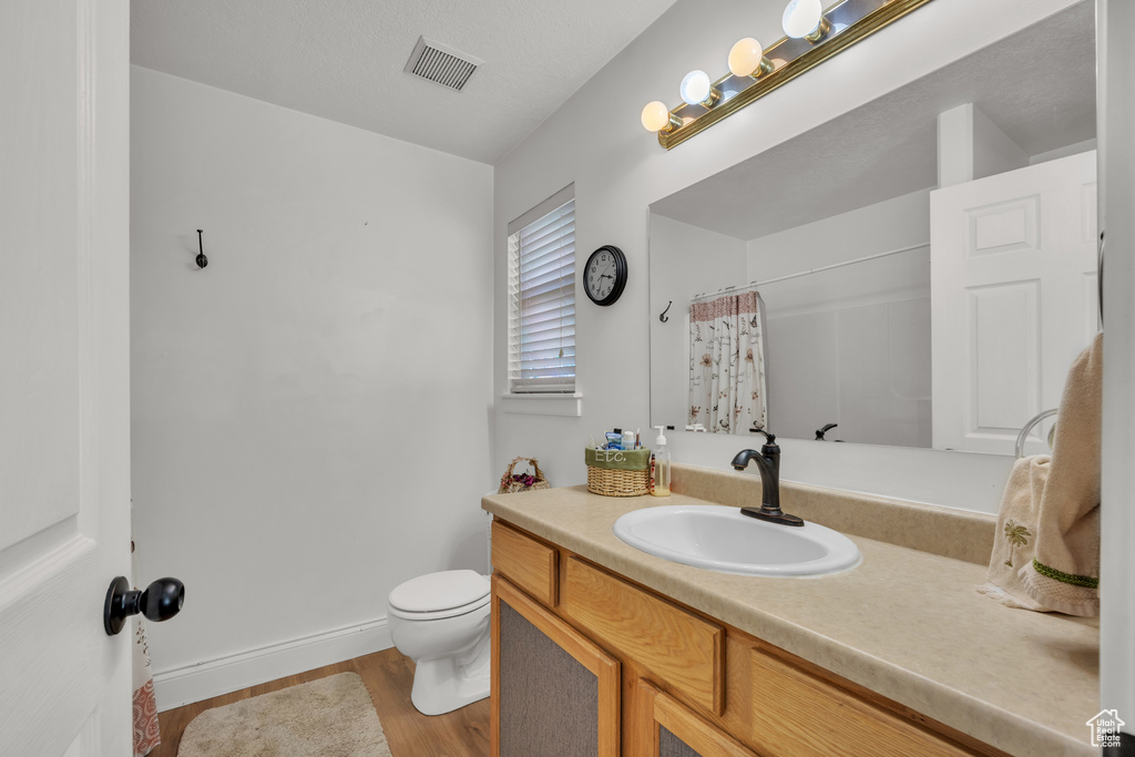 Bathroom featuring oversized vanity, hardwood / wood-style floors, and toilet