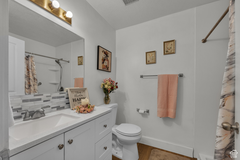 Bathroom with backsplash, hardwood / wood-style flooring, toilet, and vanity
