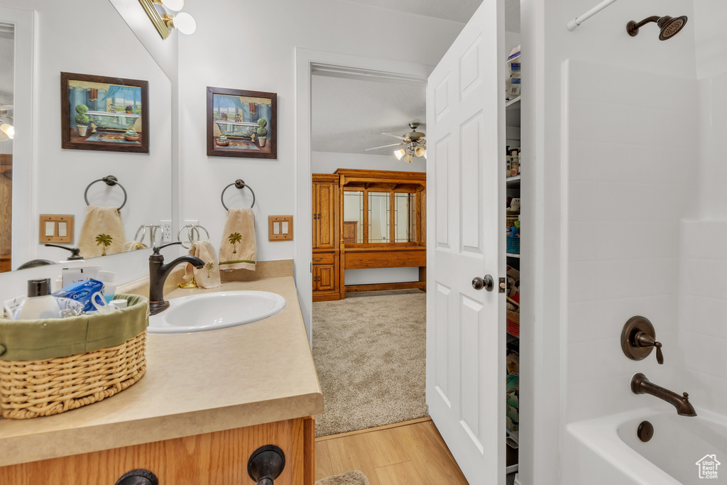 Bathroom featuring hardwood / wood-style floors, ceiling fan, vanity, and shower / washtub combination