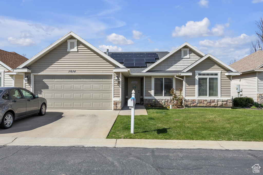 View of front facade featuring solar panels, a garage, and a front lawn