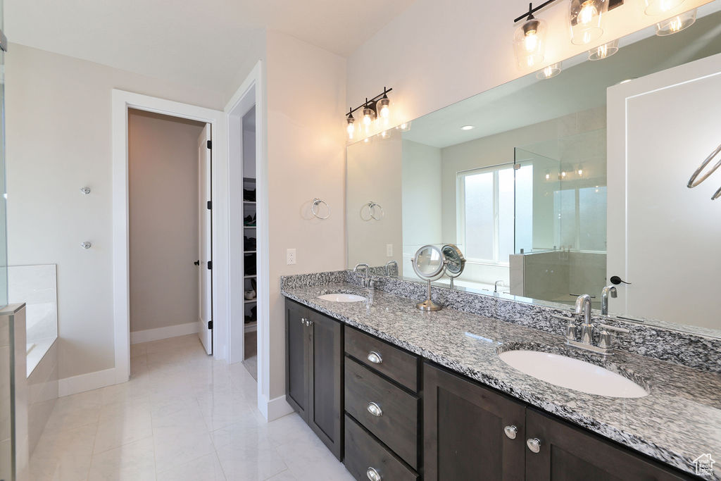 Bathroom with tile floors, vanity with extensive cabinet space, double sink, and a bath