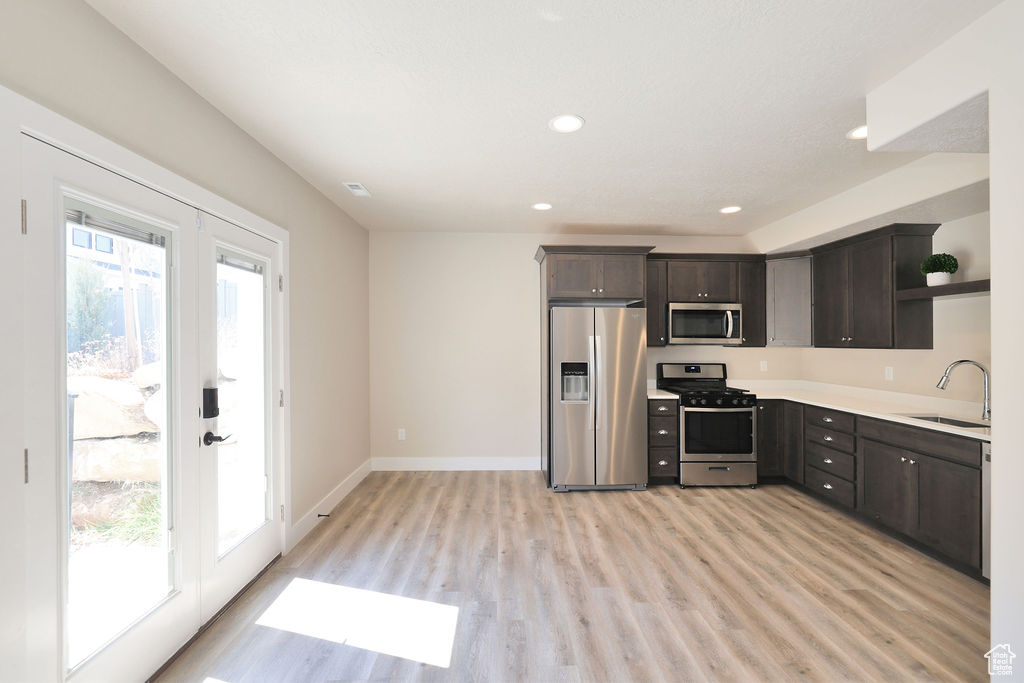 Kitchen with sink, light wood-type flooring, stainless steel appliances, and a wealth of natural light