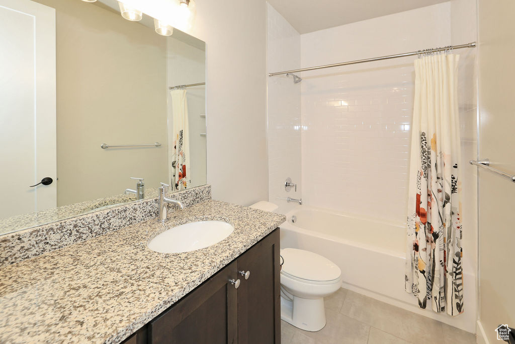 Full bathroom with shower / bath combo, tile floors, vanity with extensive cabinet space, and toilet