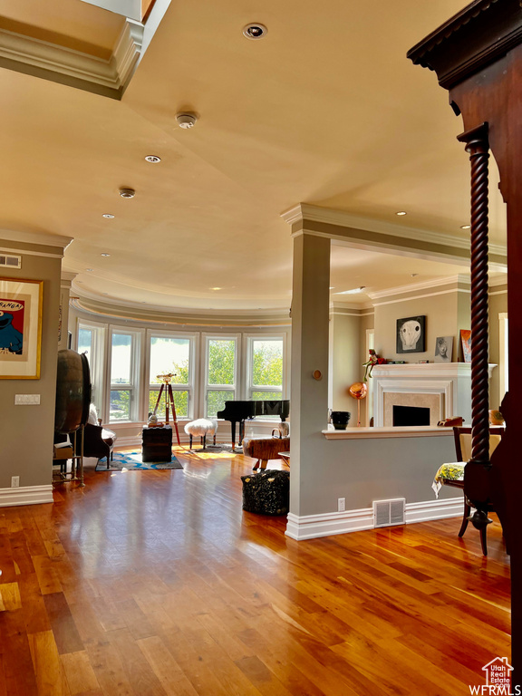Interior space with crown molding, ornate columns, and hardwood / wood-style floors