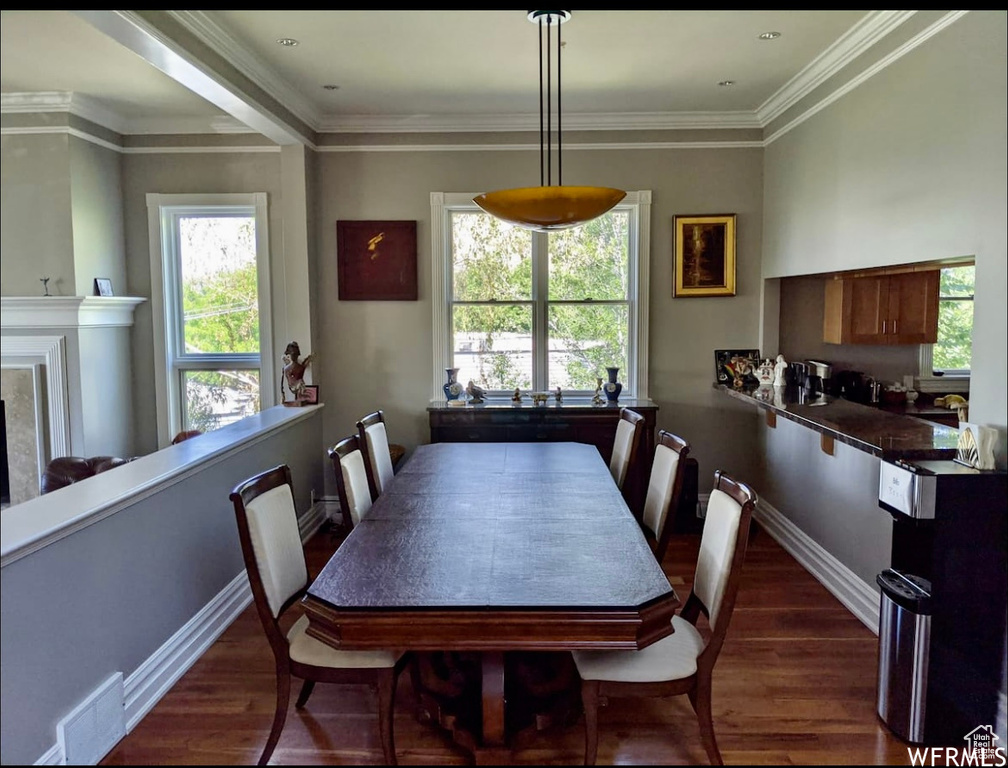Dining area featuring dark wood-type flooring and ornamental molding