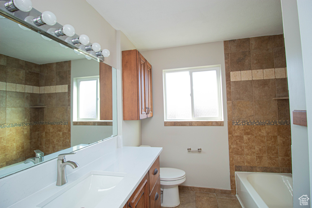 Full bathroom with vanity with extensive cabinet space, toilet, tiled shower / bath, and tile flooring