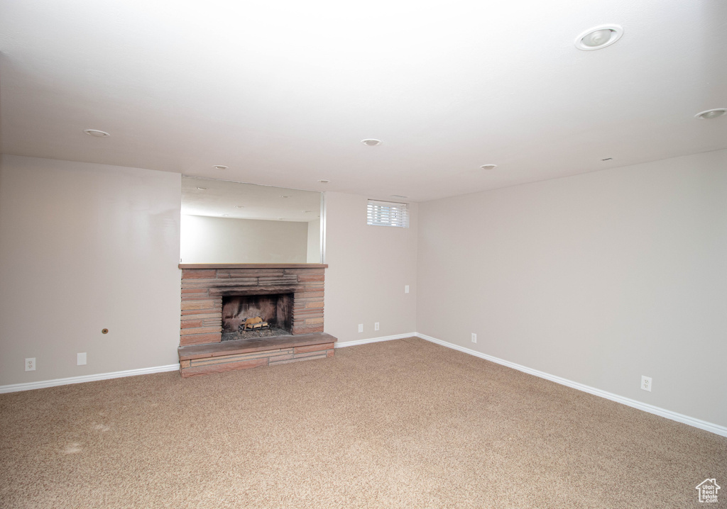 Unfurnished living room featuring light carpet and a fireplace