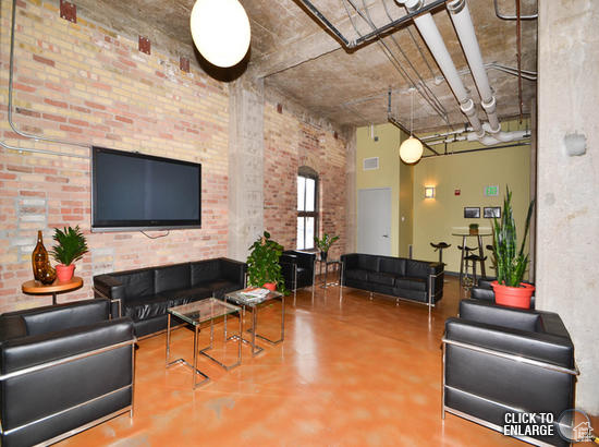 Living room featuring brick wall, concrete flooring, and a towering ceiling