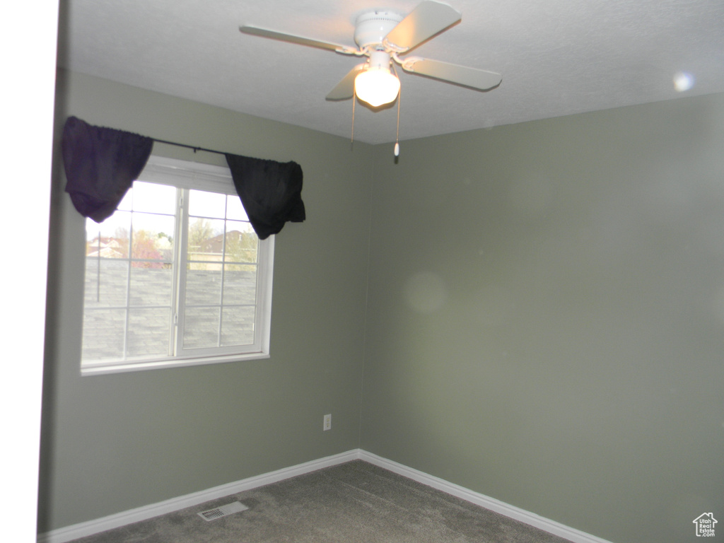 Spare room with dark colored carpet and ceiling fan