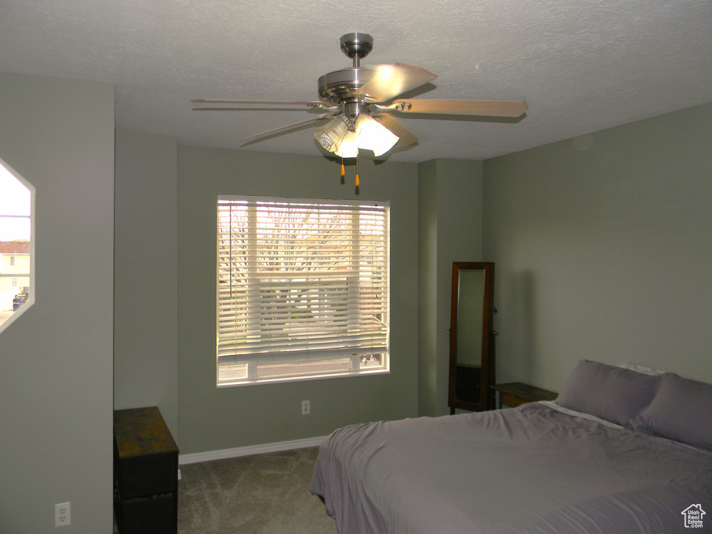 Bedroom featuring dark carpet, ceiling fan, and a textured ceiling