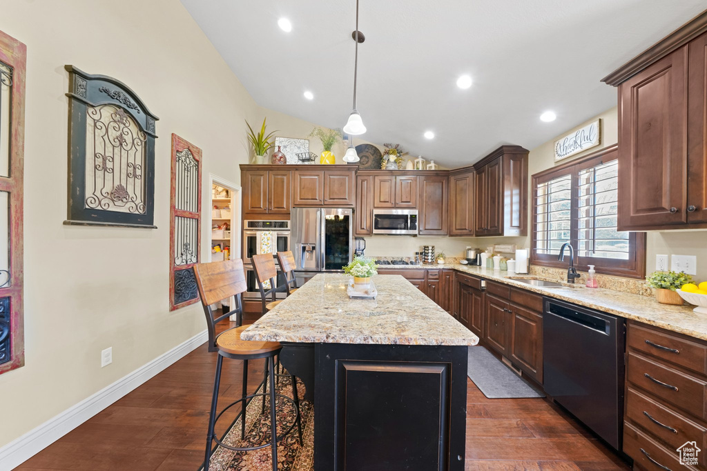 Kitchen with appliances with stainless steel finishes, a kitchen island, sink, dark hardwood / wood-style floors, and light stone countertops