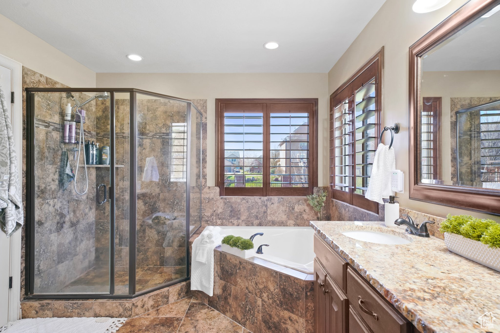 Bathroom with oversized vanity, shower with separate bathtub, and tile floors