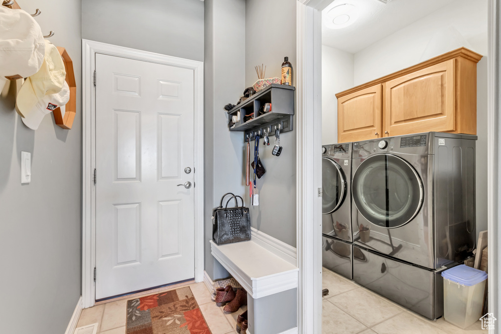 Washroom featuring cabinets, separate washer and dryer, and light tile floors