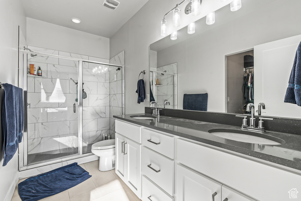 Bathroom featuring large vanity, toilet, tile flooring, an enclosed shower, and double sink