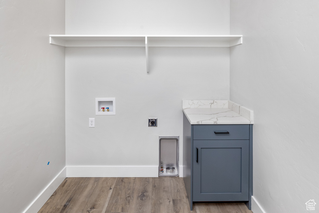 Washroom featuring hookup for an electric dryer, light hardwood / wood-style flooring, cabinets, and hookup for a washing machine