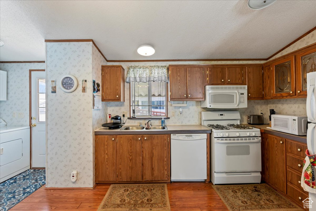 Kitchen featuring light hardwood / wood-style floors, white appliances, sink, and washer / dryer