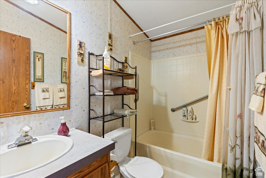 Full bathroom featuring vanity, shower / bath combo, toilet, and a textured ceiling