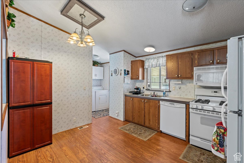 Kitchen with crown molding, light hardwood / wood-style flooring, washer / clothes dryer, and white appliances