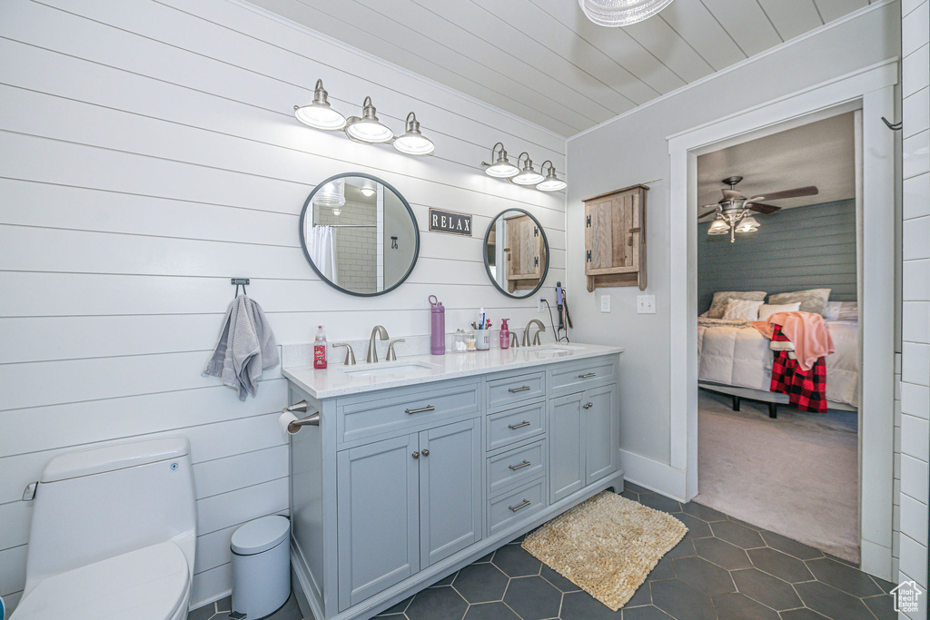 Bathroom featuring tile flooring, ceiling fan, large vanity, dual sinks, and toilet