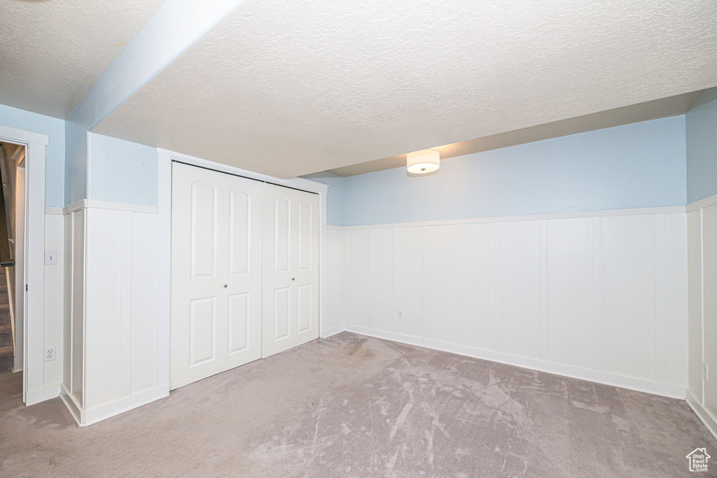 Basement with a textured ceiling and light carpet