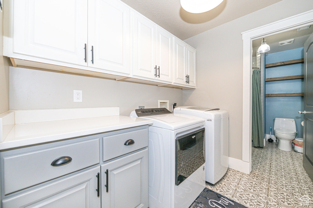 Laundry area featuring cabinets, light tile floors, washer hookup, and separate washer and dryer