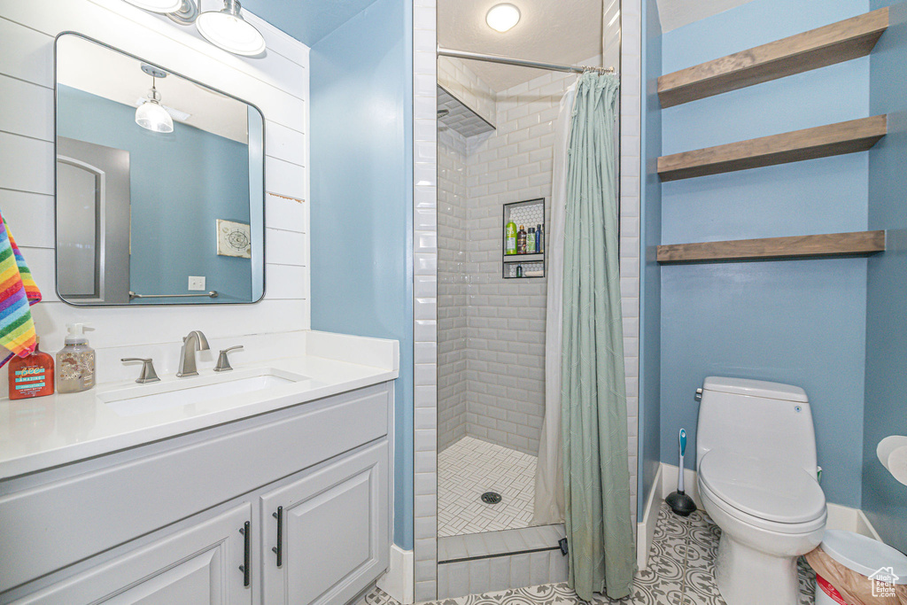 Bathroom with tile flooring, walk in shower, vanity with extensive cabinet space, and toilet