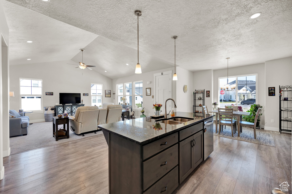 Kitchen with sink, light hardwood / wood-style floors, dark stone countertops, and pendant lighting