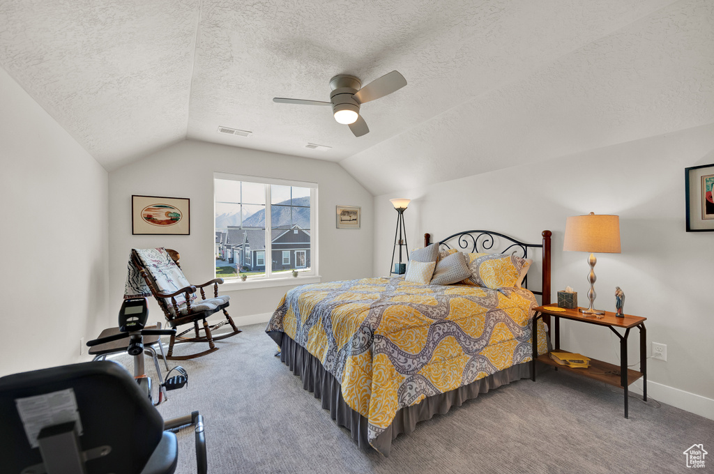 Bedroom featuring lofted ceiling, ceiling fan, light carpet, and a textured ceiling