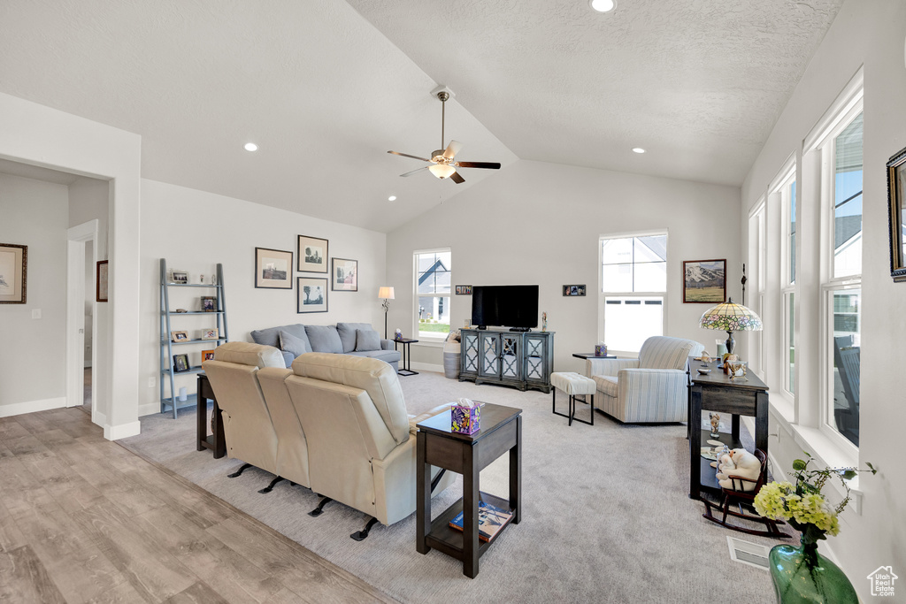 Carpeted living room featuring high vaulted ceiling and ceiling fan