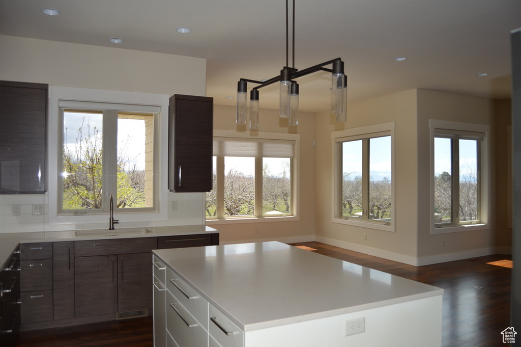 Kitchen with a kitchen island, dark hardwood / wood-style flooring, dark brown cabinetry, and sink
