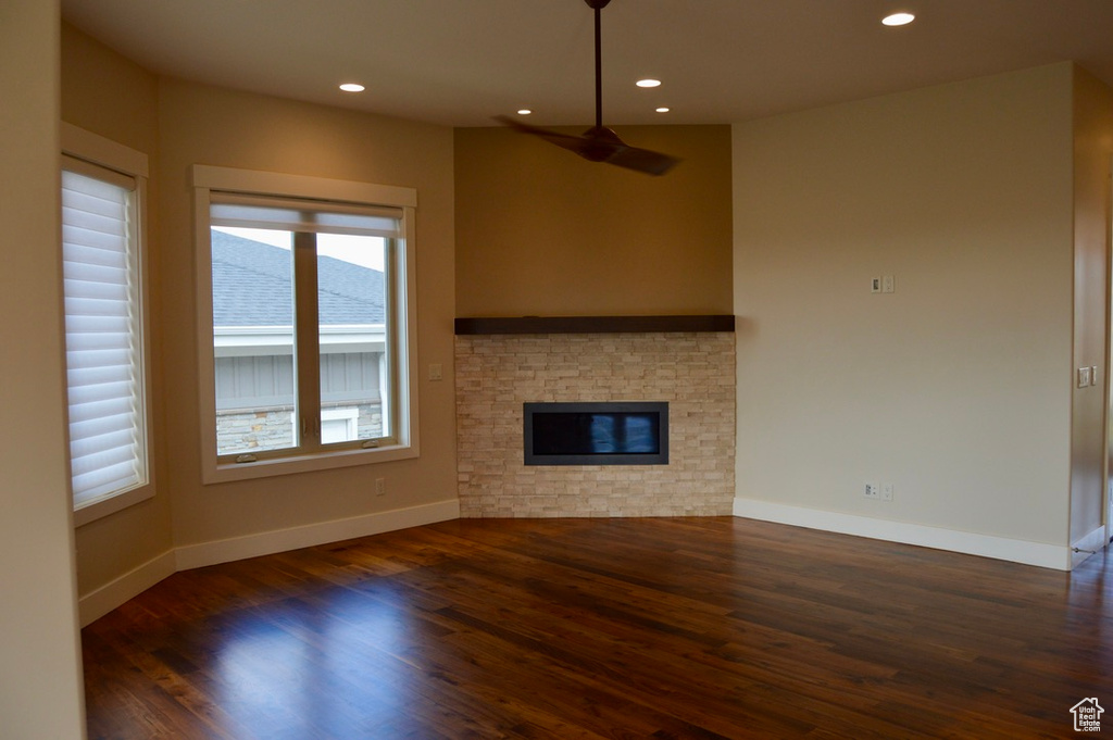 Unfurnished living room with a fireplace, dark wood-type flooring, and plenty of natural light