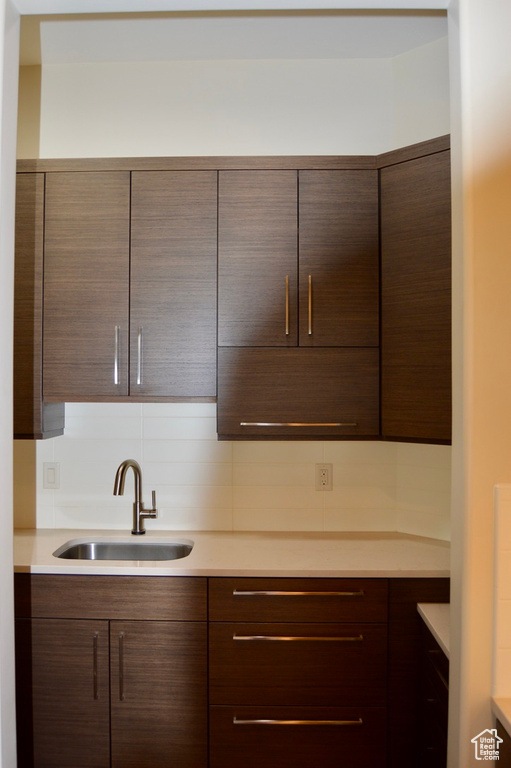 Kitchen featuring tasteful backsplash, dark brown cabinets, and sink