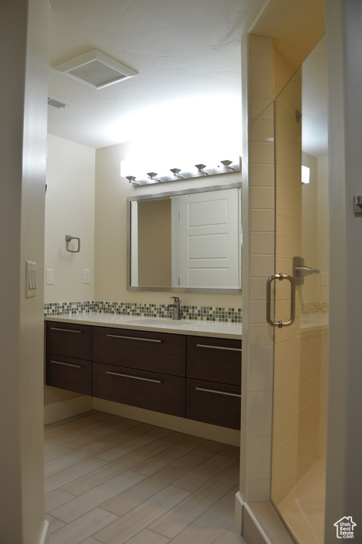 Bathroom featuring an enclosed shower, tasteful backsplash, and vanity