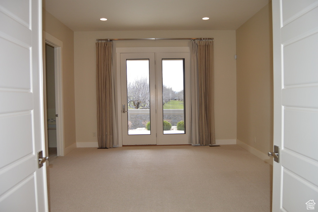 Unfurnished room featuring light carpet and french doors