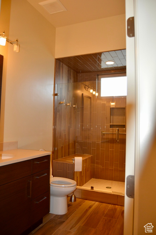 Bathroom featuring hardwood / wood-style flooring, an enclosed shower, vanity, and toilet
