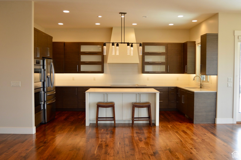 Kitchen with dark hardwood / wood-style floors, sink, a kitchen island, a chandelier, and a kitchen bar