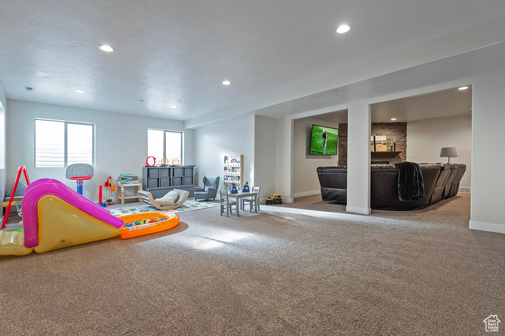 Recreation room featuring a stone fireplace and carpet floors