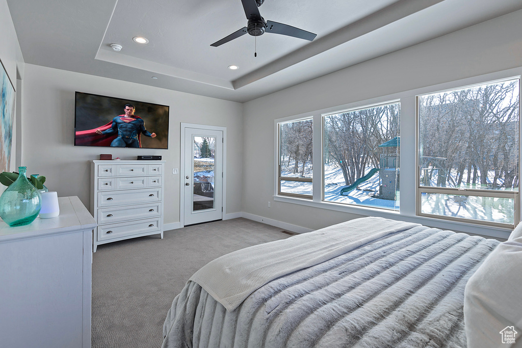 Carpeted bedroom with ceiling fan, a tray ceiling, and access to exterior