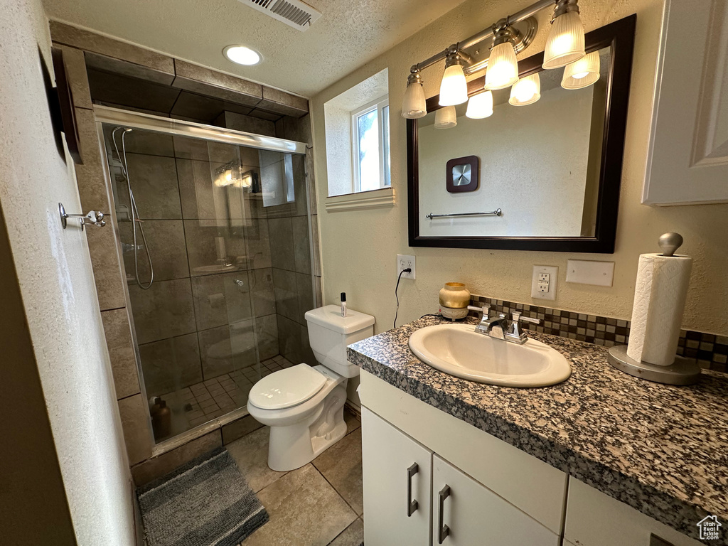 Bathroom featuring oversized vanity, a shower with shower door, toilet, a textured ceiling, and tile floors