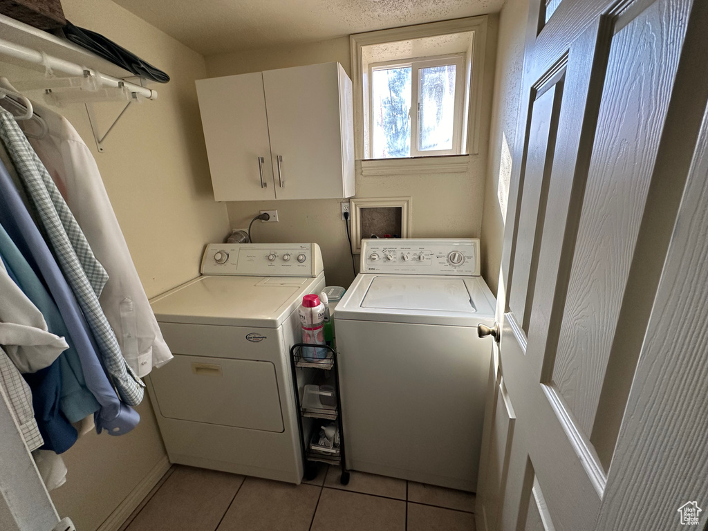 Laundry room featuring hookup for a washing machine, washing machine and dryer, cabinets, and light tile flooring