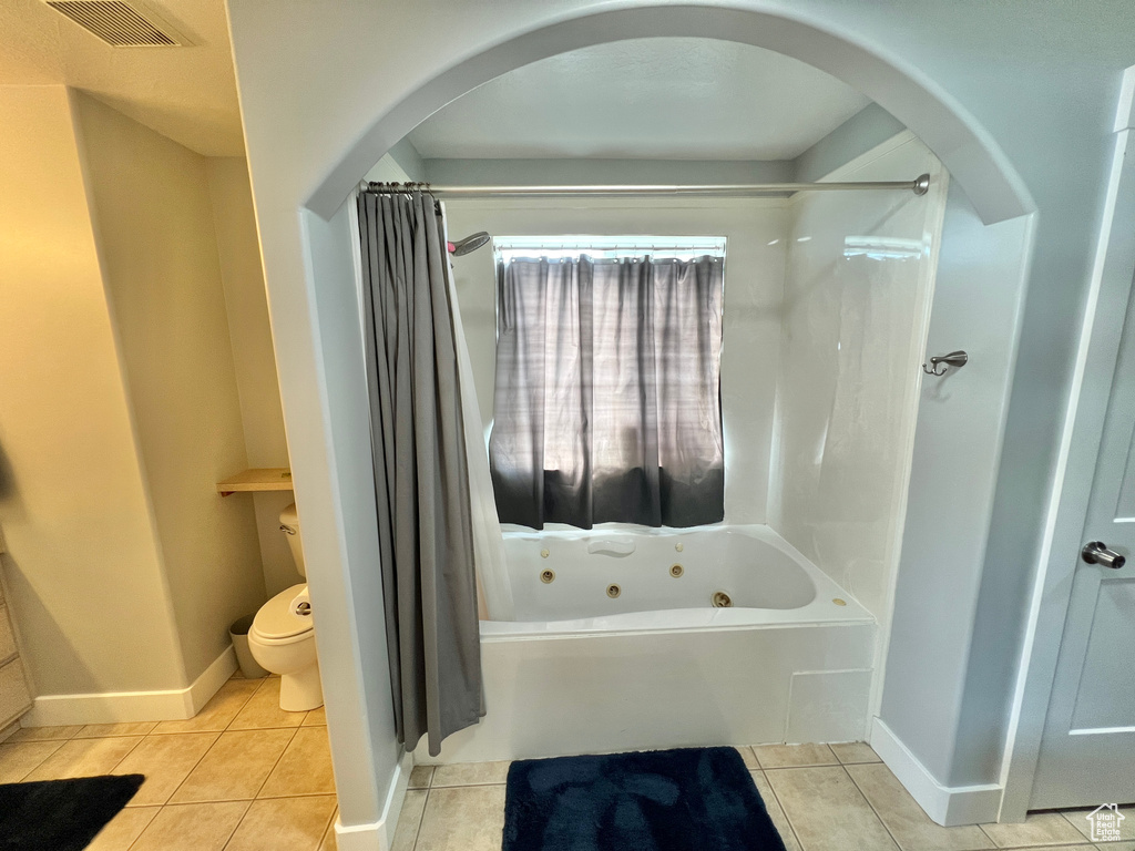 Bathroom with tile flooring, shower / tub combo, and toilet
