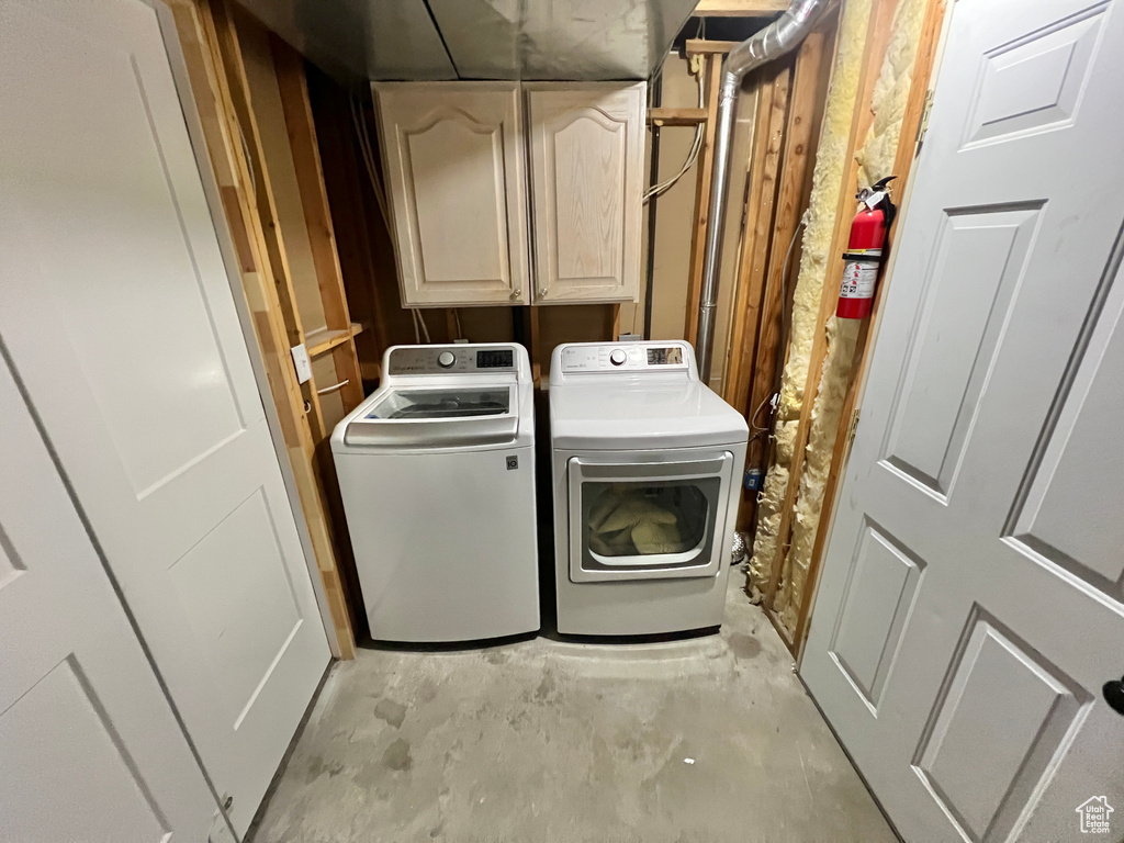 Clothes washing area featuring cabinets and washing machine and clothes dryer