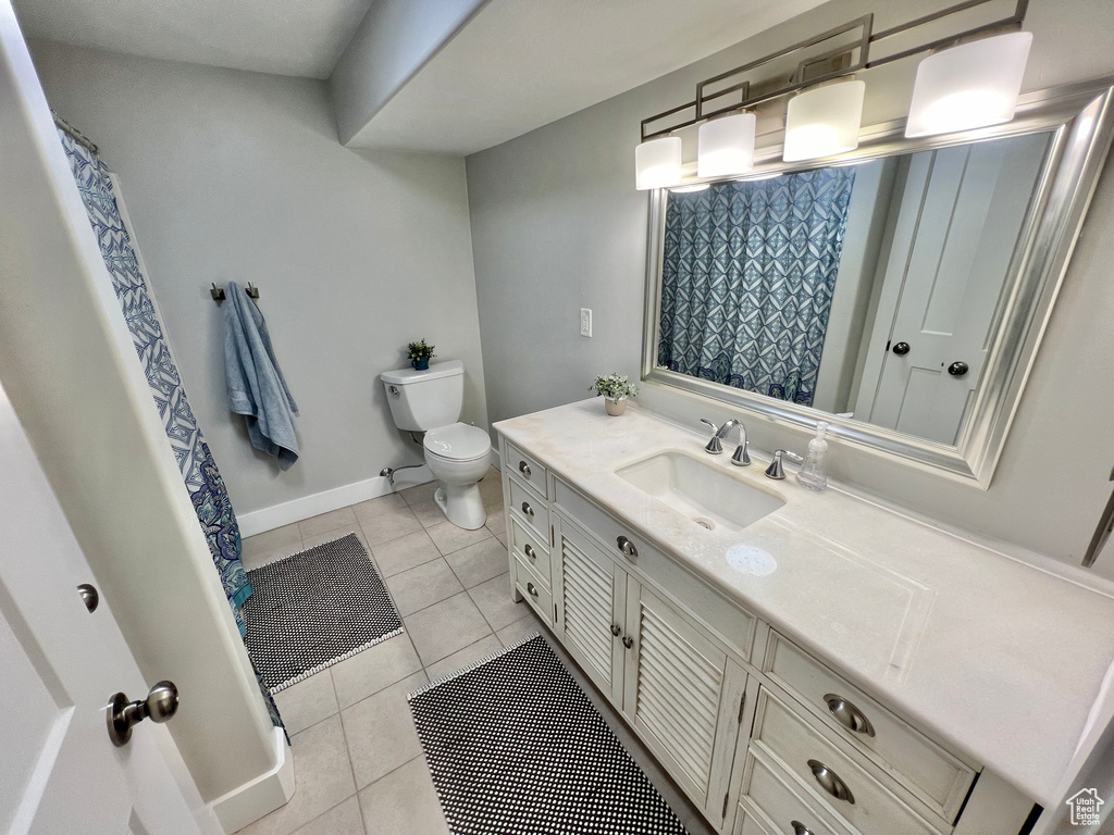 Bathroom with vanity with extensive cabinet space, toilet, and tile flooring