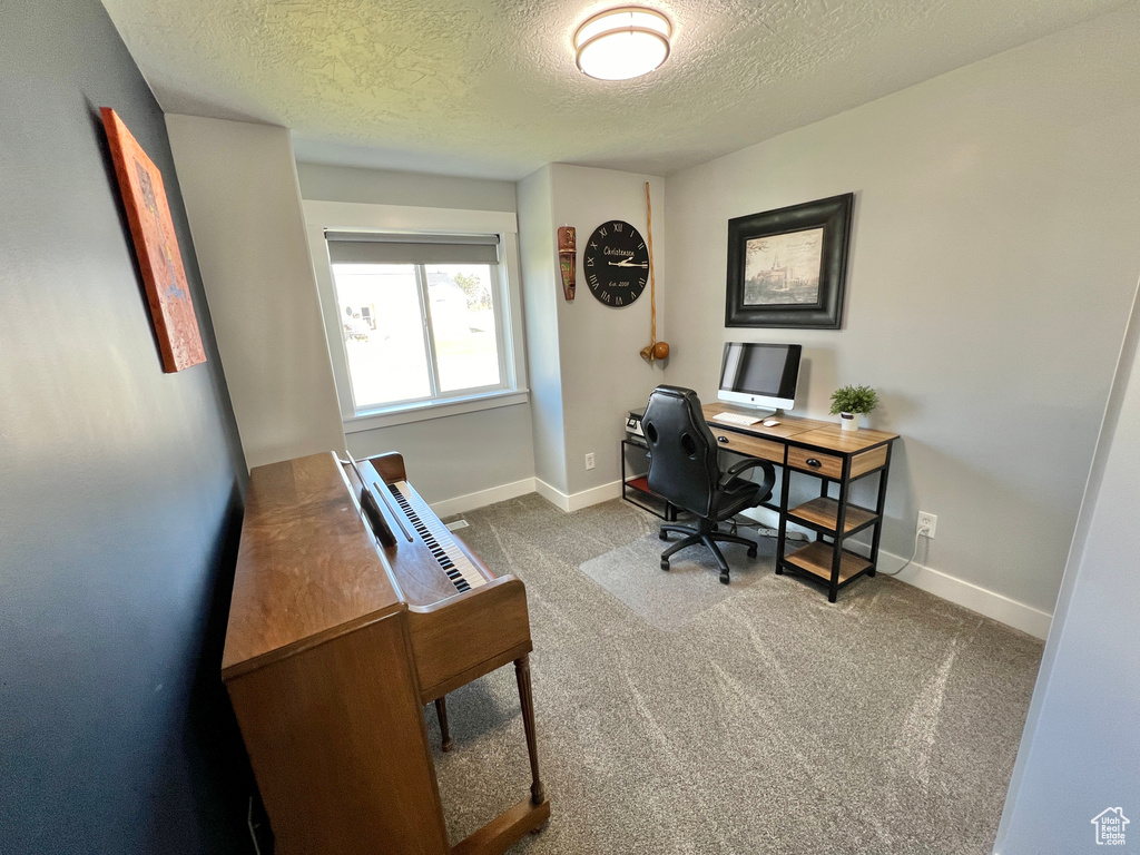 Home office featuring dark carpet and a textured ceiling