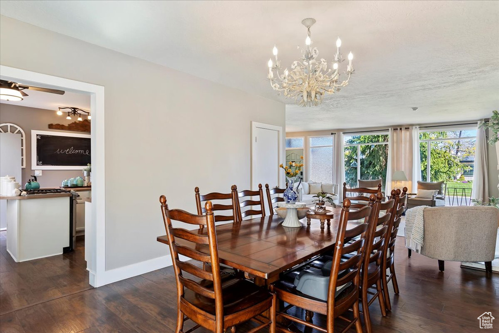 Dining space featuring ceiling fan with notable chandelier and dark hardwood / wood-style floors