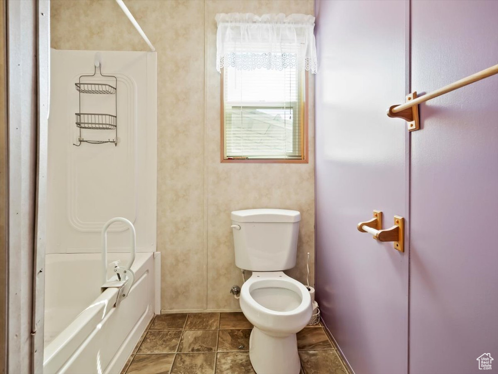 Bathroom featuring tile flooring, a tub, and toilet