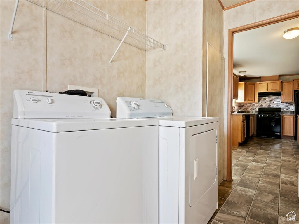 Clothes washing area with dark tile flooring, hookup for a washing machine, and washer and clothes dryer