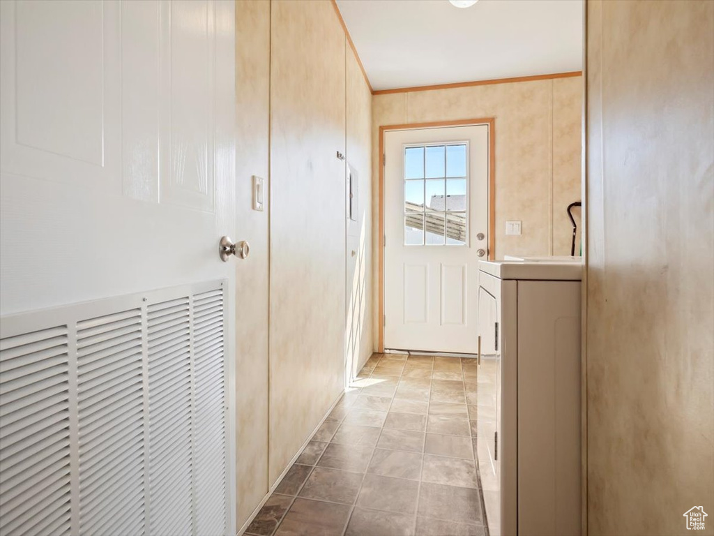 Hallway with washer / clothes dryer and light tile flooring