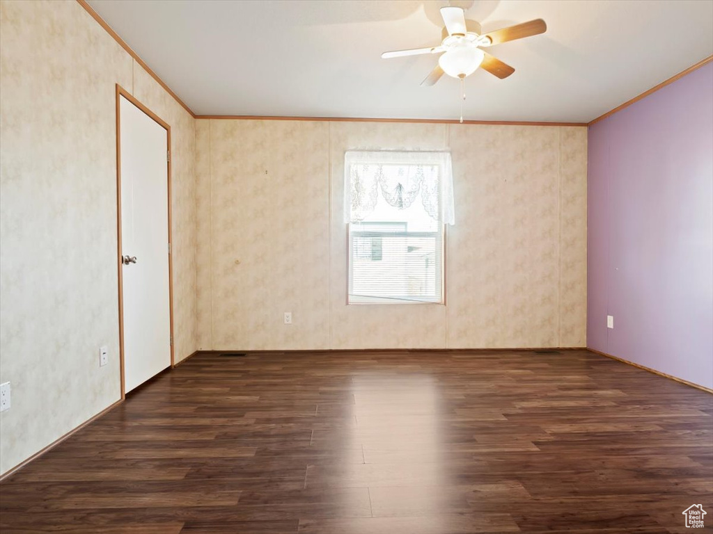 Empty room featuring crown molding, ceiling fan, and dark hardwood / wood-style floors