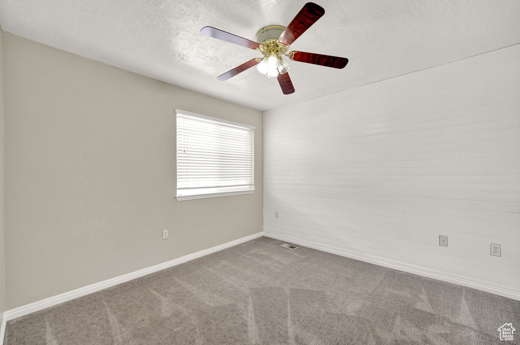 Spare room featuring carpet, ceiling fan, and a textured ceiling